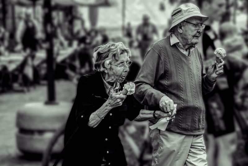Un matrimonio de personas mayores tomando helado por la calle.