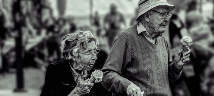 Un matrimonio de personas mayores tomando helado por la calle.